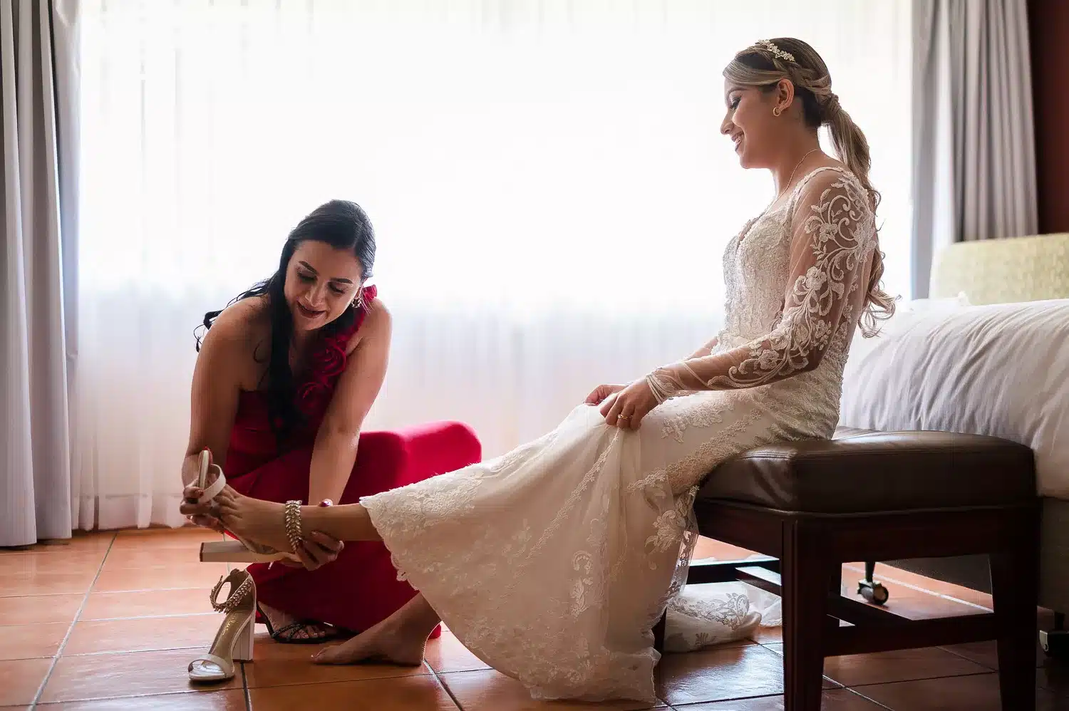 Mom of the bride helping her to put her wedding shoes at their suite in DoubleTree Cariari Hotel | Fotógrafo de Bodas Costa Rica