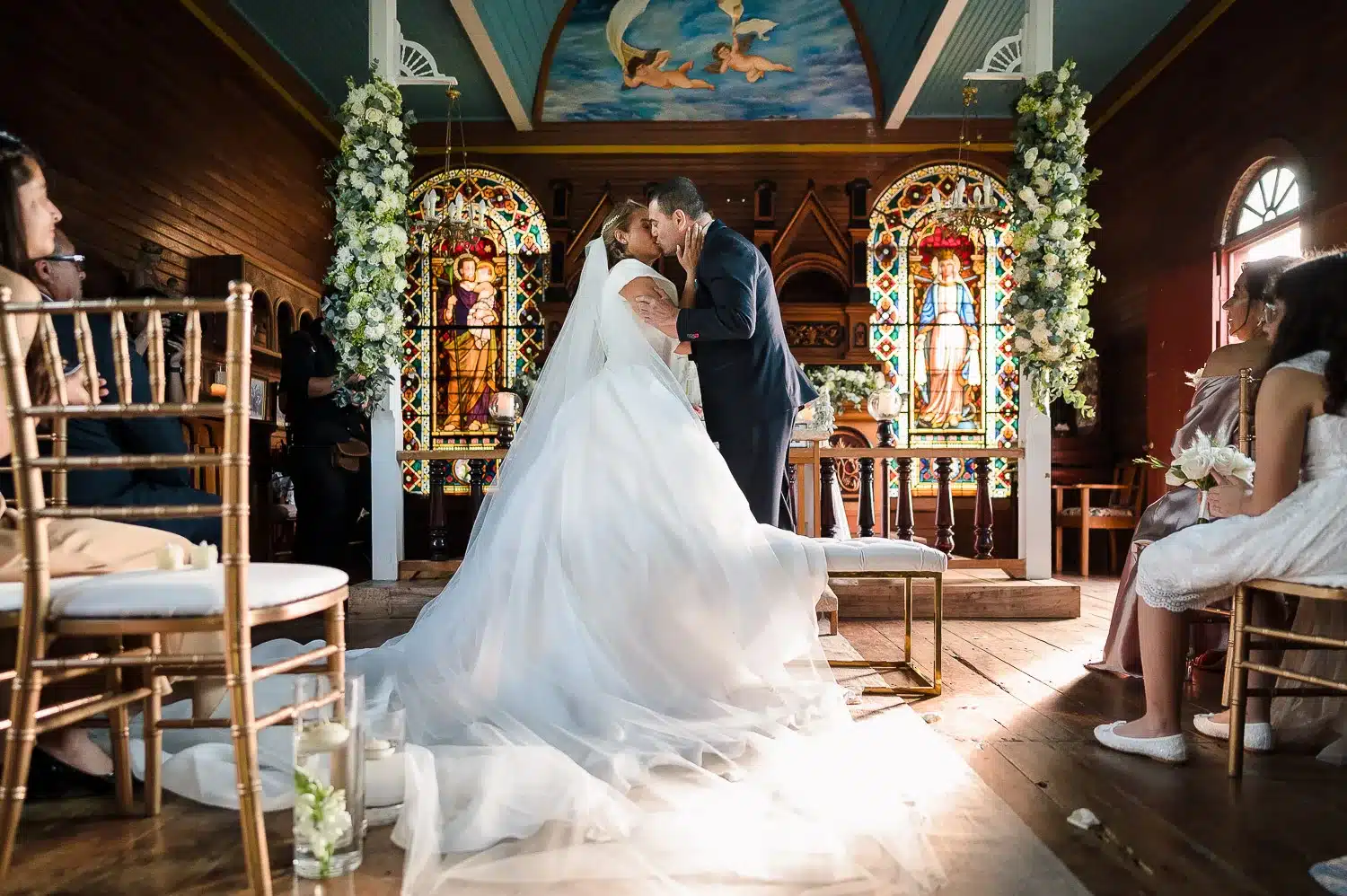 Primer beso de la nueva pareja dentro de la hermosa capilla tallada en madera.